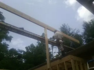 Carpenter setting a ridge beam over a new addition frame — Ice Dam Removal by Roofing Brothers in Blanco