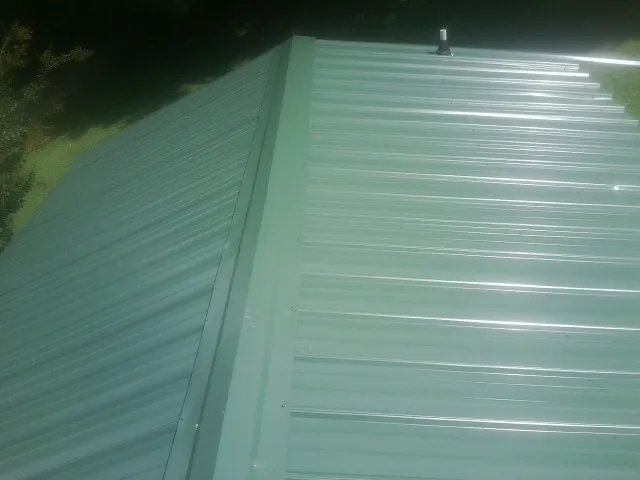 New green metal panels meeting at the ridge of a roof — Flat Roof Repair work by our crew in Blanco