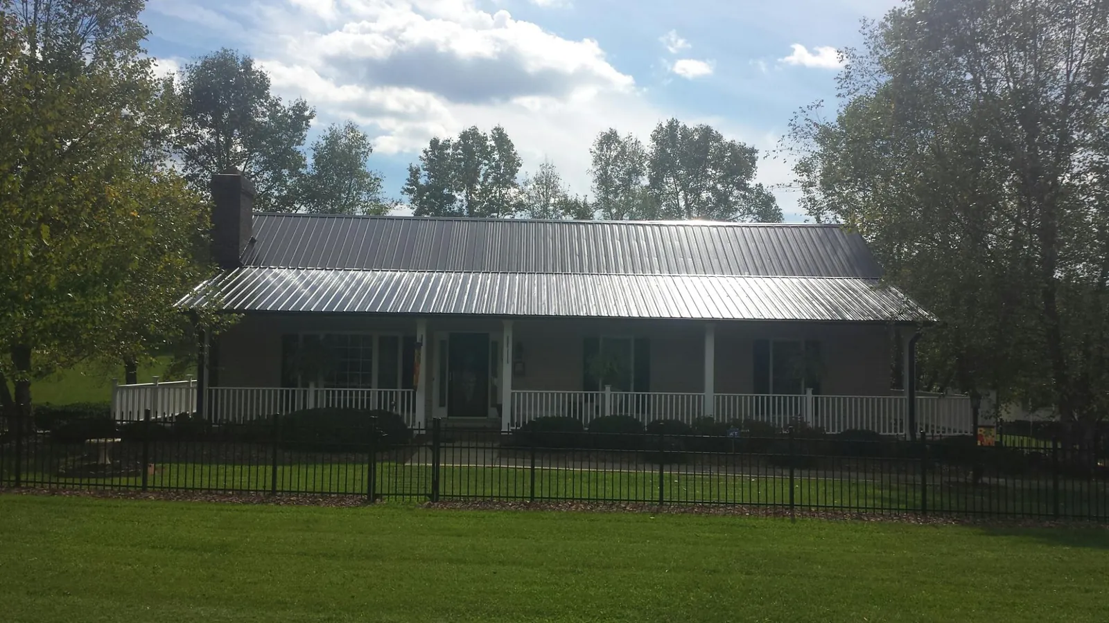 Gray metal roof on a brick ranch with a full width front porch — Gutter Guard Installation work by our crew in Blanco