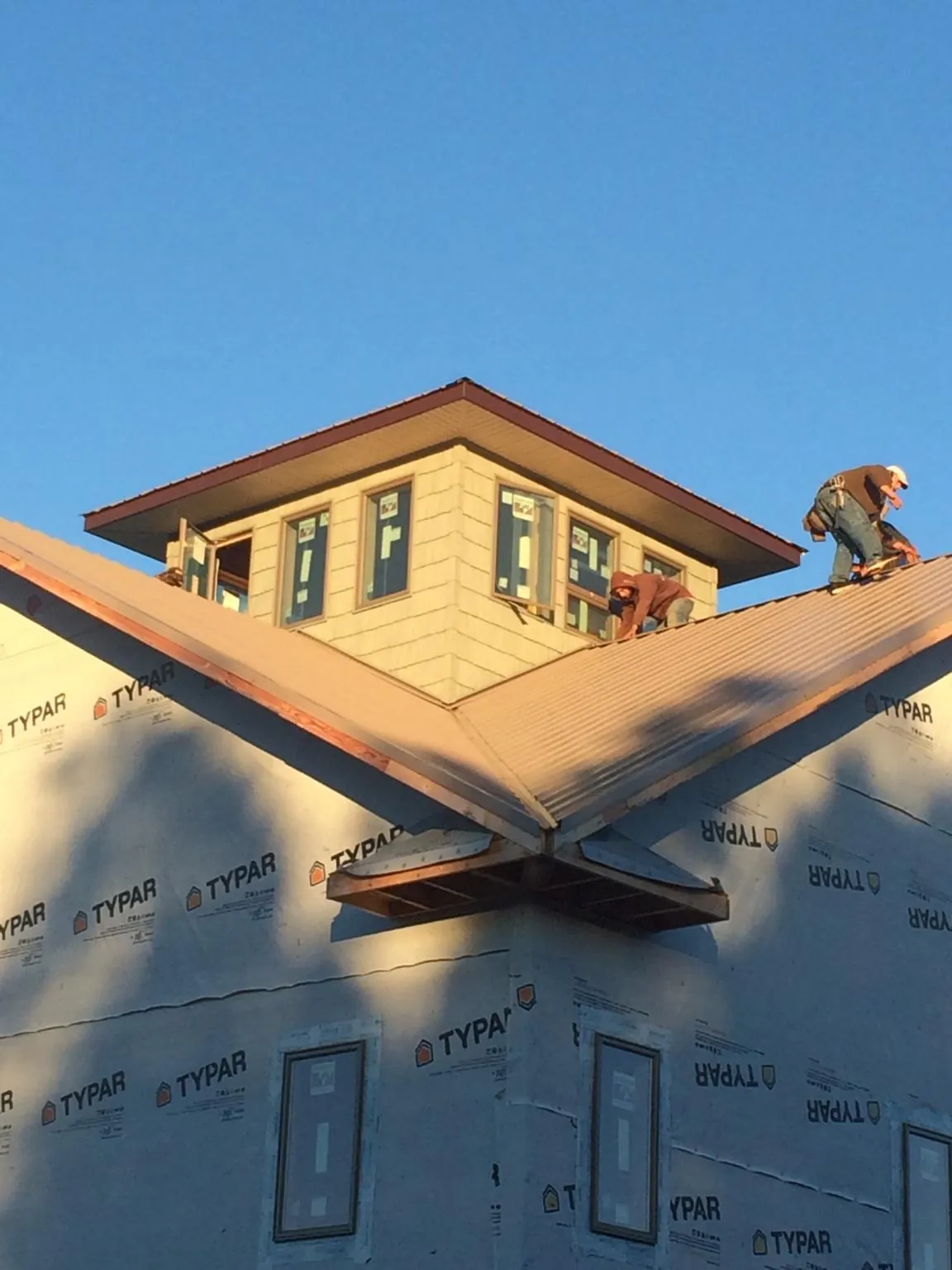 Roofers working around a rooftop cupola on a new metal roof at sunset — Roof Waterproofing in Blanco by Roofing Brothers